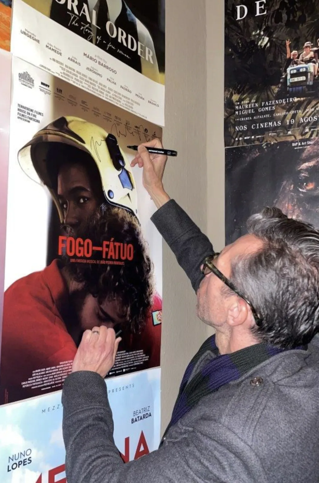 A director signs the poster for Fogo-Fátuo