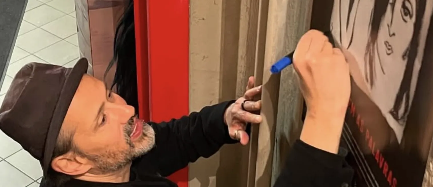 A director signs a festival poster on the wall