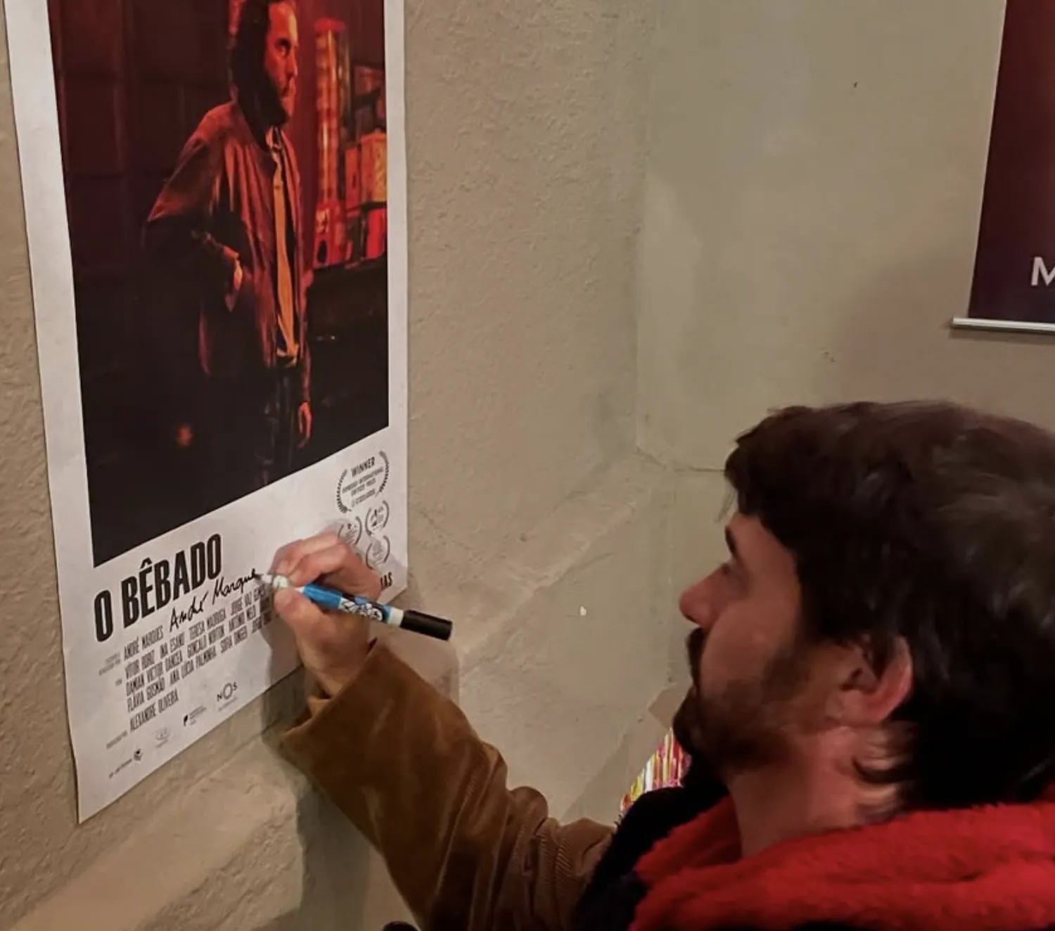 A director signs the poster for O Bêbado